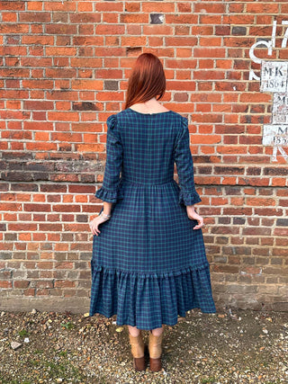 women wearing tartan dress by brick wall
