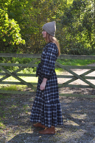 woman stood by gate wearing dress side view