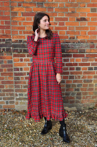 women by wall wearing red check dress